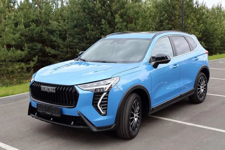 Голубой кроссовер Haval Jolion на парковке у соснового леса